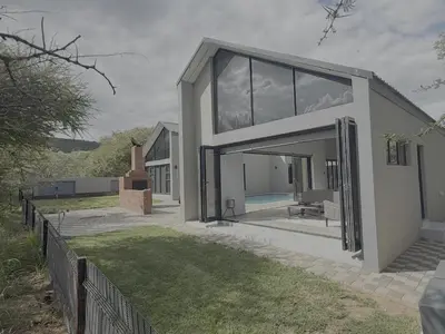 a house with a large glass door in a yard at Kambula Villa 374 Euphoria in Naboomspruit