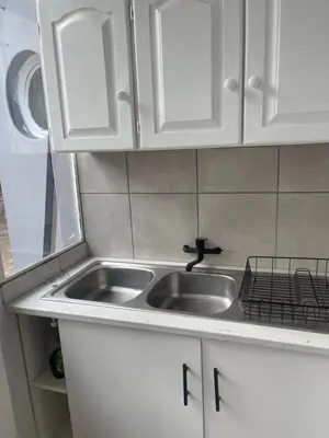 a kitchen counter with a sink and white cabinets at Lani Accommodation in Pretoria