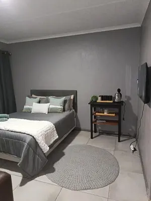 a bedroom with a bed and a television and a rug at J & M Elegant escape 2 in Centurion