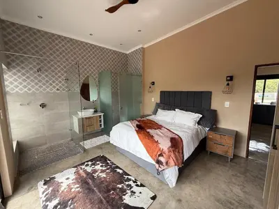 a bedroom with a large bed and a shower at Blessed Lodge at Ingilozi Mabalingwe in Warmbaths