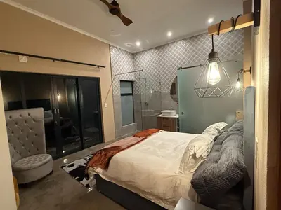 a bedroom with a large bed and a bathroom at Blessed Lodge at Ingilozi Mabalingwe in Warmbaths