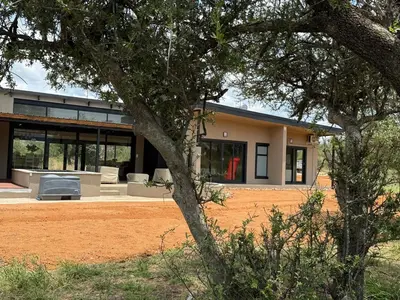 a house with a lot of windows and a tree at Blessed Lodge at Ingilozi Mabalingwe in Warmbaths