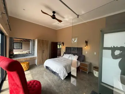 a bedroom with a bed and a glass door with a camera at Blessed Lodge at Ingilozi Mabalingwe in Warmbaths