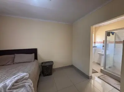 a bedroom with a bed and a bathroom with a shower at Divine apartments in Polokwane