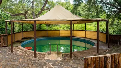 a gazebo over a swimming pool with a tent at Pafuri Accommodation Rivercamp in Tshikuyu