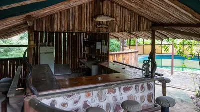 a room with a table and a swimming pool at Pafuri Accommodation Rivercamp in Tshikuyu