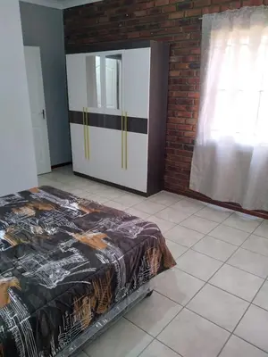 a bedroom with a bed and a brick wall at The Pasture Loft in Mokopane