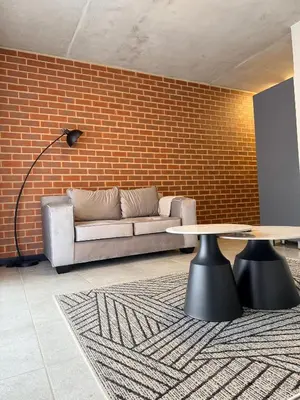 a living room with a couch and a table and a brick wall at Sunset Sucasa in Midrand