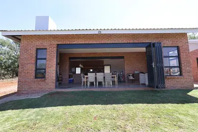 a brick house with a patio with tables and chairs at Elements Private Golf Reserve 123 in Warmbaths