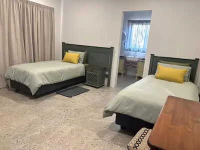 a room with two beds and a desk and a table at Elements Private Golf Reserve 123 in Warmbaths