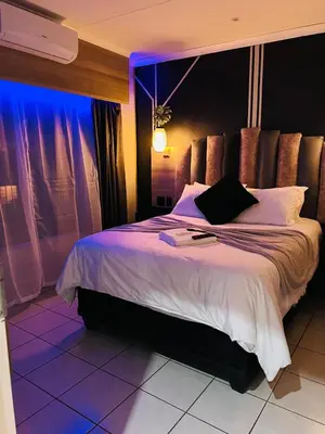 a bedroom with a large bed with purple lighting at The Wired Nest in Ellisras
