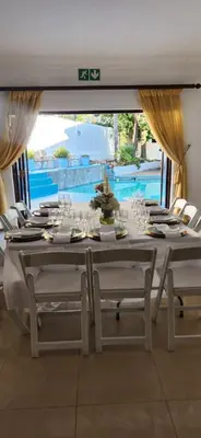 a white table with white chairs and a table set for a meal at 165 Neptune Waterkloof Pretoria in Pretoria