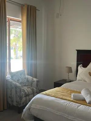 a bedroom with a bed and a chair and a window at 165 Neptune Waterkloof Pretoria in Pretoria