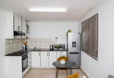 a kitchen with a table and a white refrigerator at Serenity on Geelhaak in Kempton Park