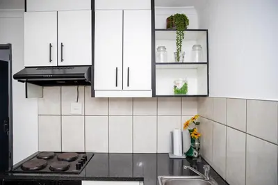 a kitchen with white cabinets and a stove top oven at Serenity on Geelhaak in Kempton Park