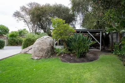 a garden with a large rock and a building at Serenity on Geelhaak in Kempton Park