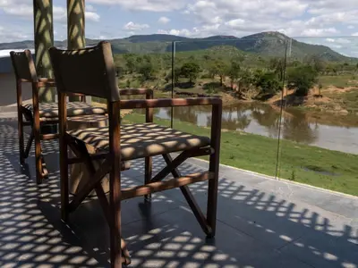 two chairs sitting on a porch looking out at a river at Izakithi River Villa in Malelane
