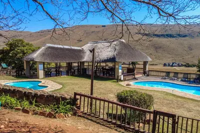 a resort with a thatch roof and a swimming pool at Doornkop Luxury 8 Sleeper with Private Pool and Boma in Carolina