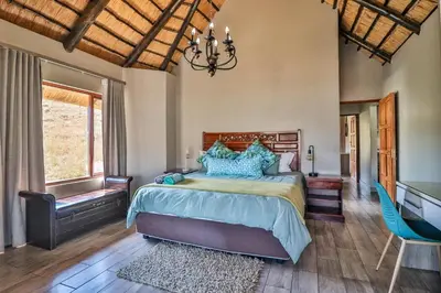 a bedroom with a bed and a desk in it at Doornkop Luxury 8 Sleeper with Private Pool and Boma in Carolina