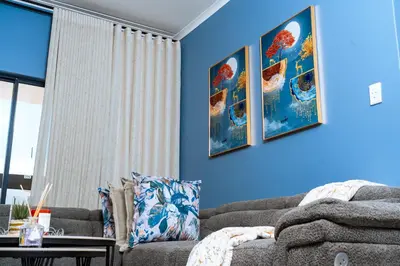 a living room with a couch and a blue wall at Fully Equipped Modern 2-Bedroom in Midrand