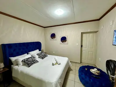 a bedroom with a large bed with a blue headboard at Grand Inn Hotel-Venda in Thohoyandou