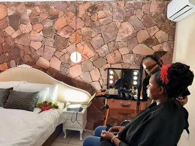 a woman sitting in front of a mirror in a bedroom at Grand Inn Hotel-Venda in Thohoyandou