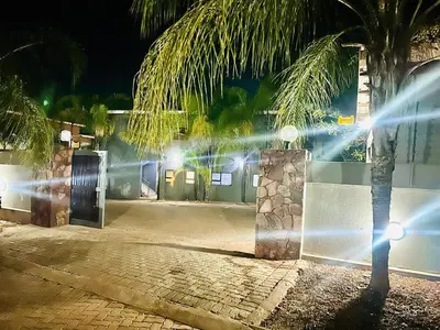 a palm tree in front of a building at night at Grand Inn Hotel-Venda in Thohoyandou