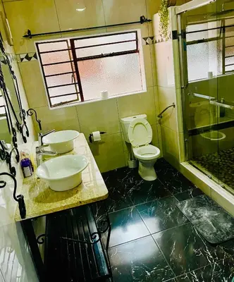 a bathroom with a toilet and a sink and a shower at QHAWEKAZI GUEST HOUSe in Witbank