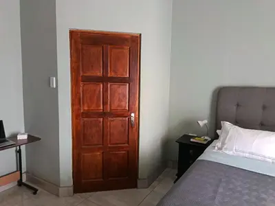 a bedroom with a wooden door next to a bed at Villa De Lyden in Lydenburg