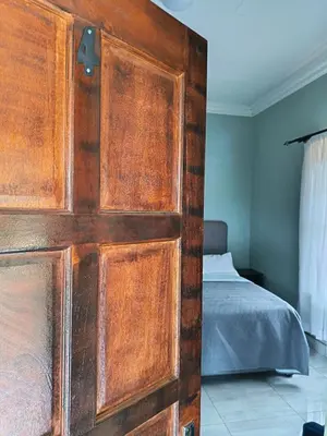 a wooden door in a bedroom with a bed at Villa De Lyden in Lydenburg