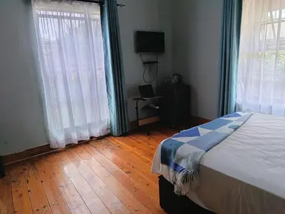 a bedroom with a bed and two large windows at Villa De Lyden in Lydenburg