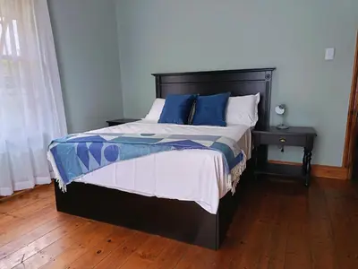 a bedroom with a large bed with blue pillows at Villa De Lyden in Lydenburg
