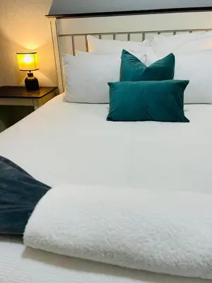 a white bed with blue pillows on it at Rugare Haven 2 in Kempton Park