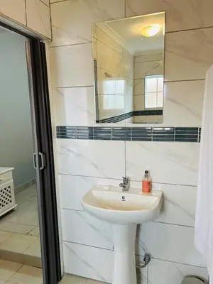 a white bathroom with a sink and a mirror at Rugare Haven 2 in Kempton Park