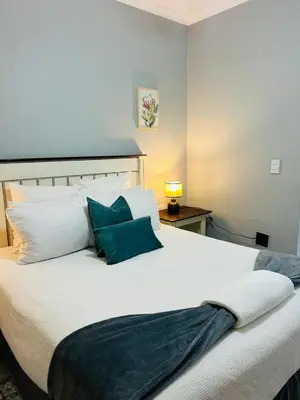 a bedroom with a large white bed with blue pillows at Rugare Haven 2 in Kempton Park