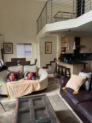 a living room with a couch and a table and a kitchen at Mona Lisa No5 in Polokwane