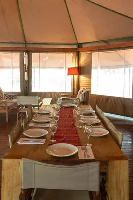 a long wooden table with plates and wine glasses at Iphofolo Lodge & Tented Camp in Vivo