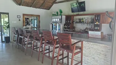 a bar with a row of wooden bar stools at Iphofolo Lodge & Tented Camp in Vivo