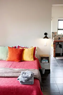 a bedroom with a red bed with colorful pillows at Pecan and Lime Inn The Third Den in Pretoria