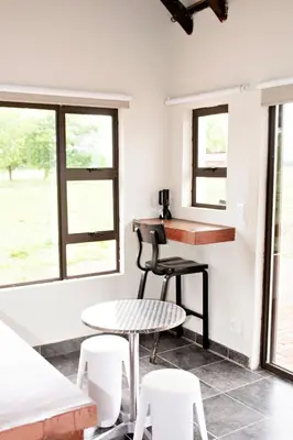 a room with a table and chairs and windows at Pecan and Lime Inn The Third Den in Pretoria