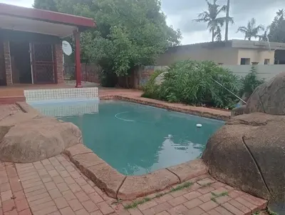 a swimming pool in front of a house at El Elyon Lodge in Pretoria
