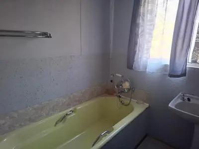 a bathroom with a green tub and a sink at AmaZeng farmhouse Mustang in Lydenburg