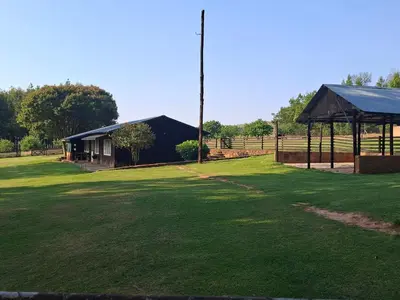 a large yard with a black building and a grass field at AmaZeng farmhouse Mustang in Lydenburg