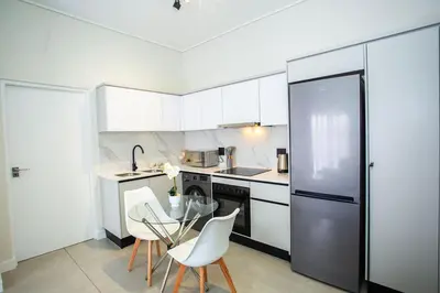 a kitchen with a glass table and white cabinets at Waterfall Midrand Lifestyle Luxe in Midrand