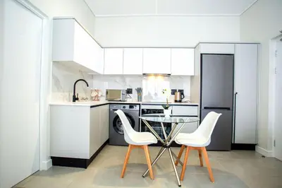 a kitchen with a table and two white chairs at Waterfall Midrand Lifestyle Luxe in Midrand