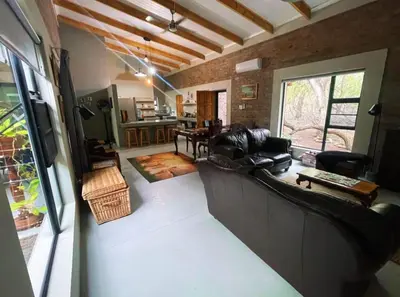 a living room with a leather couch and a table at Kudu House-Solar & Water Backup in Marloth Park