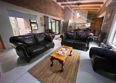 a living room with leather furniture and a coffee table at Kudu House-Solar & Water Backup in Marloth Park