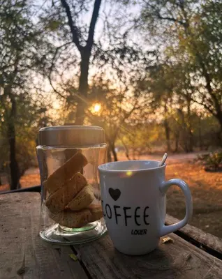 a cup of coffee and a cup of cookies on a table at Kudu House-Solar & Water Backup in Marloth Park