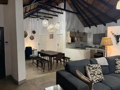 a living room and kitchen with a couch and a table at Giraffe Bush by J & J in Marloth Park