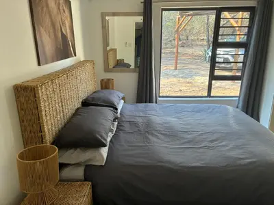 a bed with two pillows on it next to a window at Giraffe Bush by J & J in Marloth Park